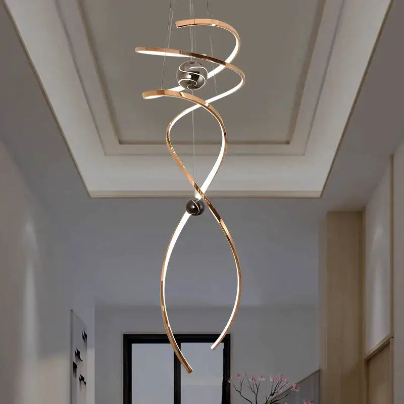 A modern gold-toned decorbites led staircase pendant light with metallic rings and black spherical accents
