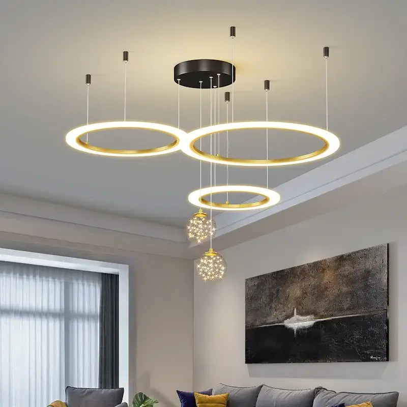 Modern gold-toned circular decorbites led star chandelier with black mounting plate and crystal globe pendants for living rooms