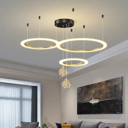 Modern gold-toned circular decorbites led star chandelier with black mount and crystal globe pendants for living room decor