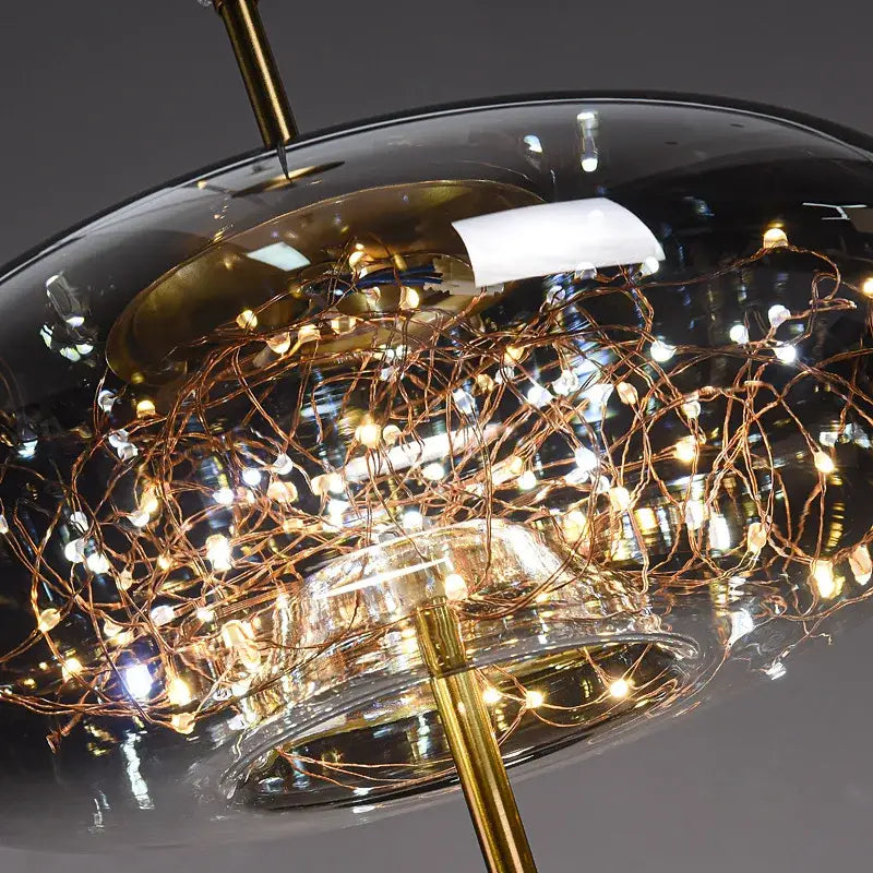 A modern glass dome pendant light with gold metal frame and copper wire string lights in decorbites led starry sky style