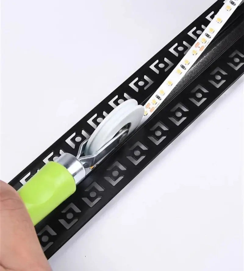 Black led strip light with geometric pattern being rolled onto aluminum profile using DecorBites™ strip light installation tool
