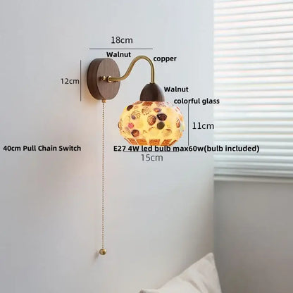 A warm-toned decorbites led tiffany style wall sconce with walnut base, copper arm, and colorful shell patterned glass shade