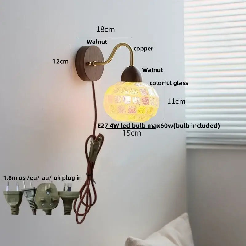A warm glowing decorbites led tiffany style wall sconce with walnut wood base copper arm and colorful mosaic glass lampshade