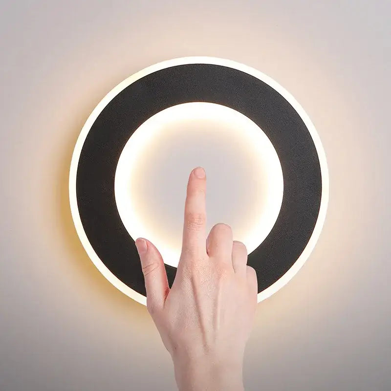 Modern circular wall light decorbites led touch switch with sleek black and white design and warm ambient glow