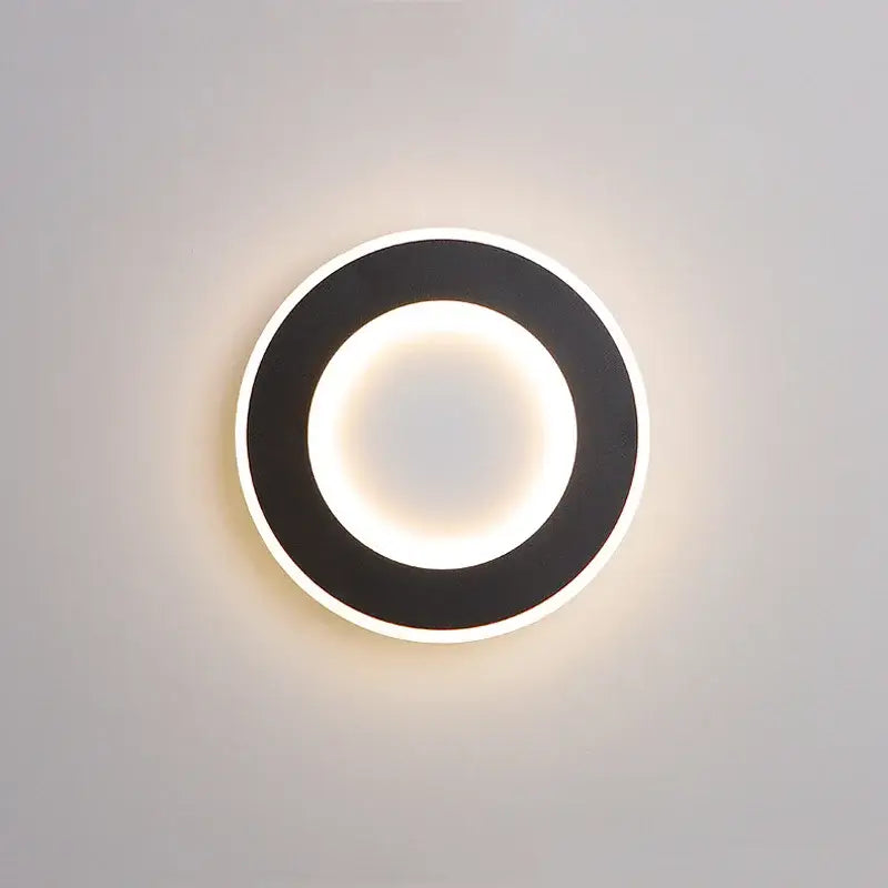 Modern black circular DecorBites LED touch wall light with glowing white inner ring for bedroom bedside use
