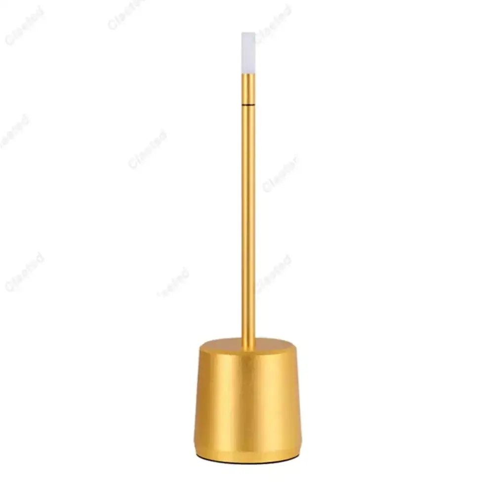 Gold-colored metal toilet brush stand with sleek cylindrical base and slender handle shown with DecorBites led touch table lamp