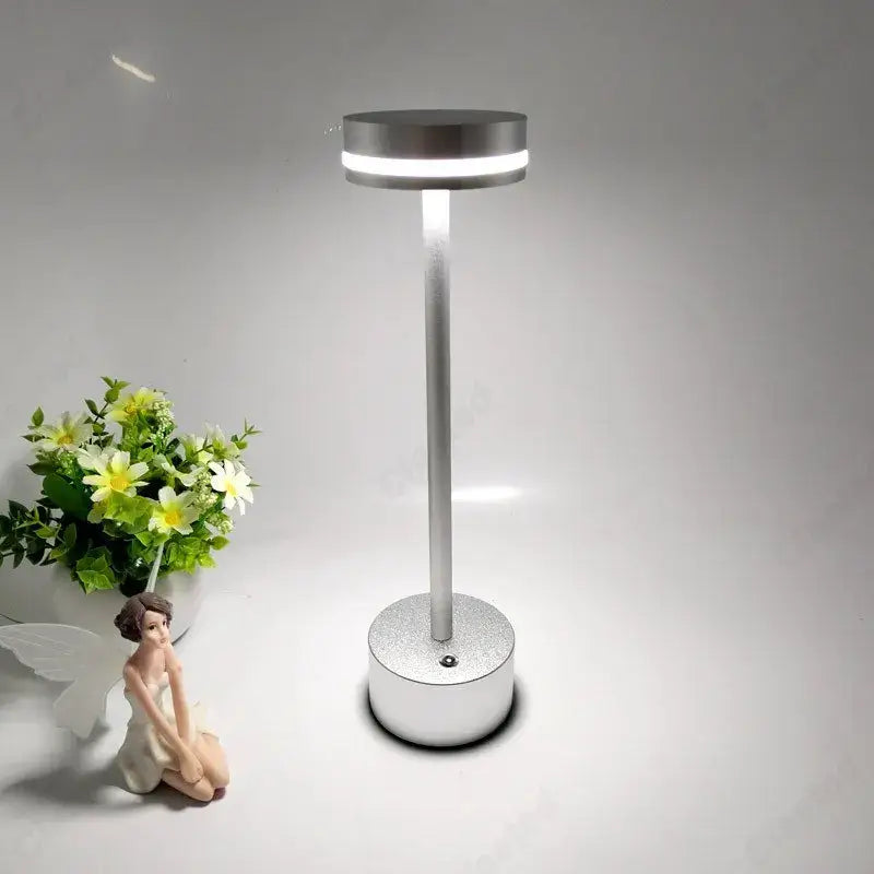 A sleek silver metallic decorbites led touch table lamp with rechargeable three-tone lighting for living room use