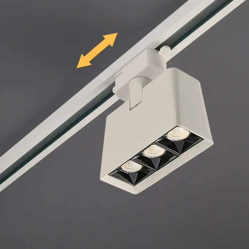 White rectangular DecorBites LED track light with three bright bulbs in a black triangular array for commercial use