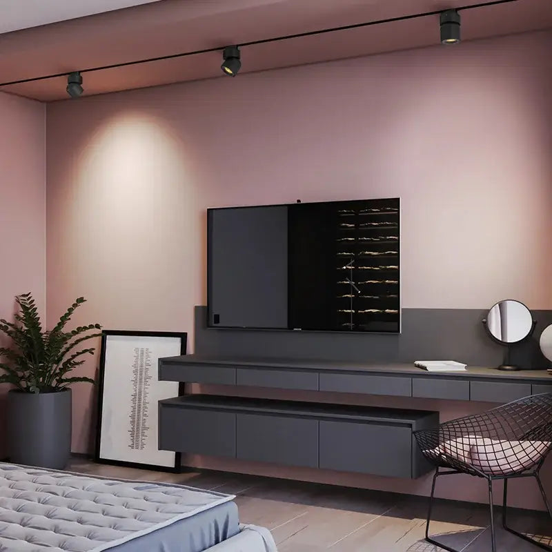 Black flat-screen television mounted on pink wall above gray console illuminated by decorbites led track light spotlight rail