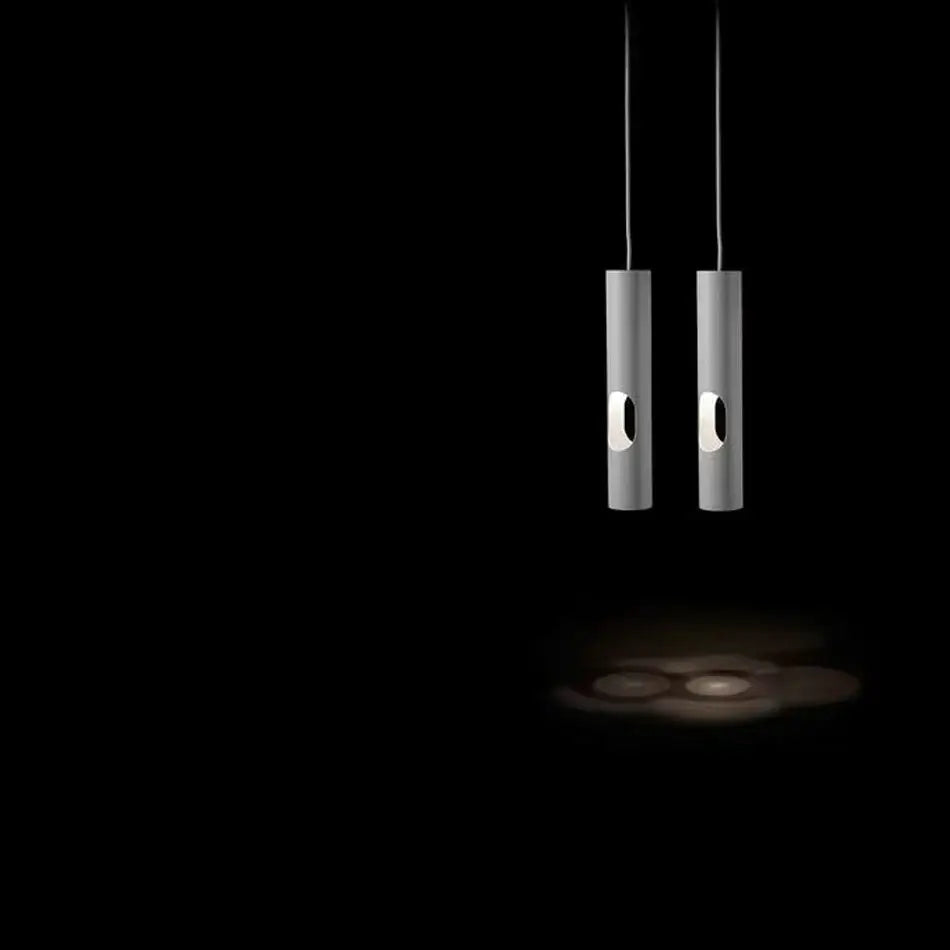Two matte silver decorbites led tube surface mount pendant lights with oval cutouts softly illuminate a dark living room