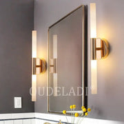 Gold-finished decorbites led tube wall sconces with frosted glass tubes flank a rectangular mirror for modern interiors