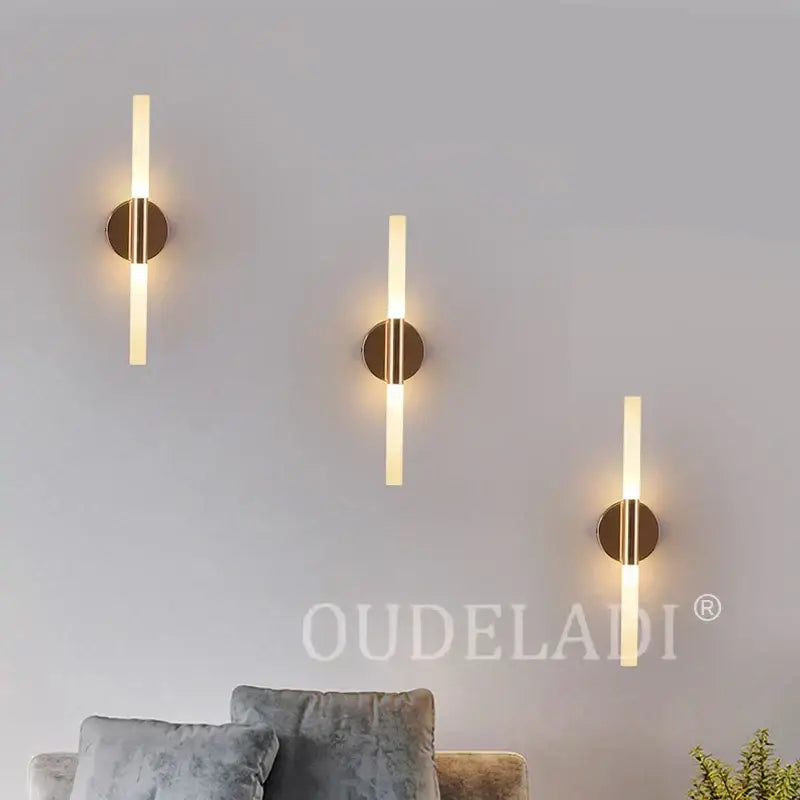 Three modern decorbites led tube wall lights with frosted glass and brass bases emitting warm glow for bedroom and foyer