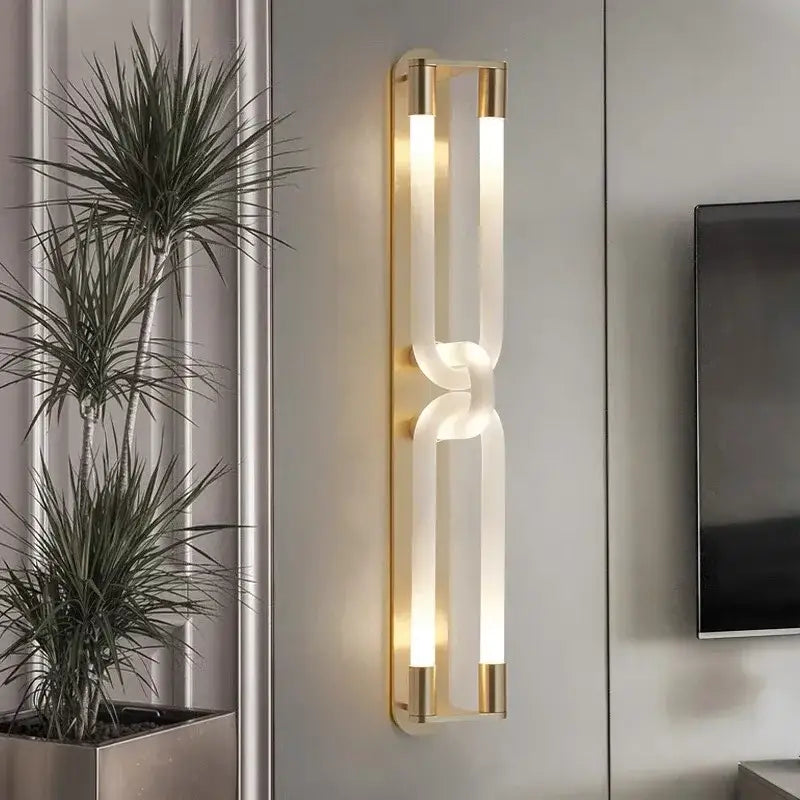 Modern gold-toned DecorBites LED tube wall sconce with two illuminated acrylic tubes in sleek interlocking design