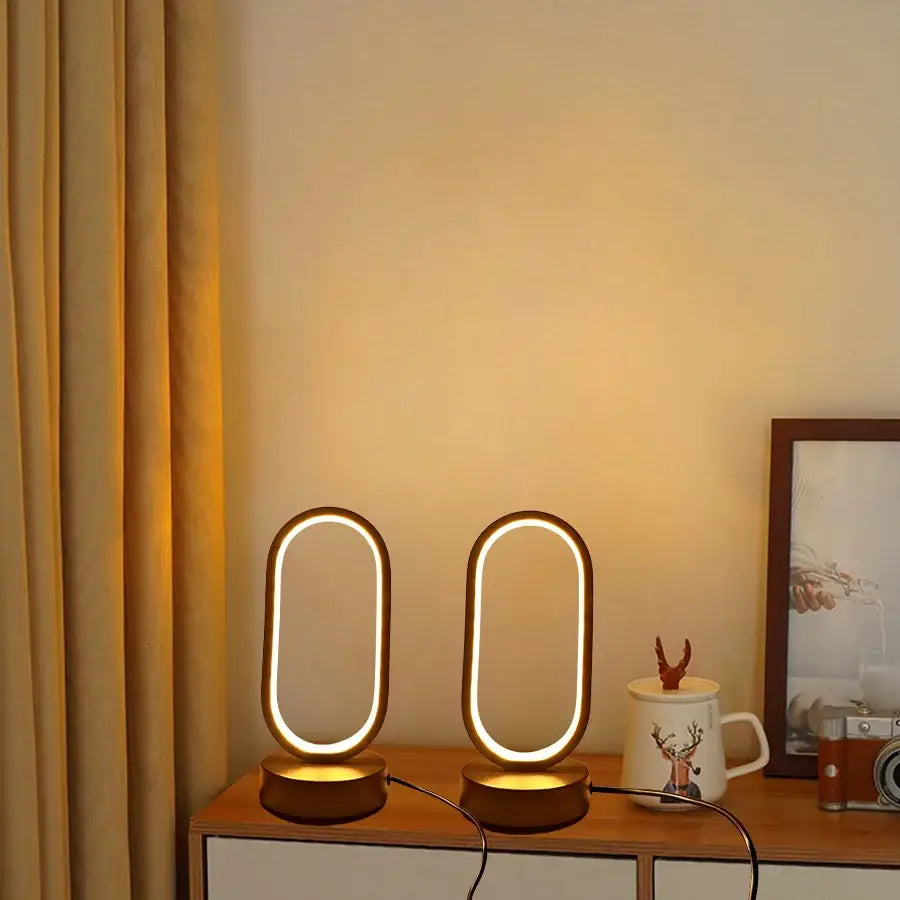 Two sleek oval-shaped warm glowing led bedside decorative lamps with minimalist metallic frame for lamp bedroom bedside use