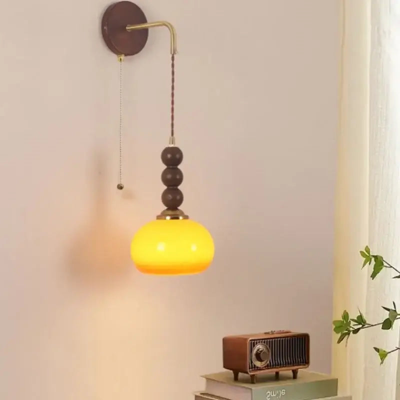 Warm yellow glass pendant lamp with brass accents and dark wood beads featured in decorbites led wall lighting