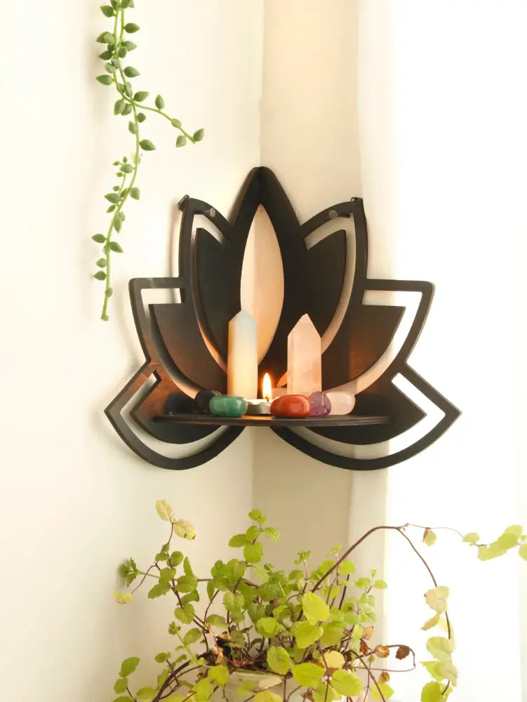 Black metal lotus floating wall shelf holding candles and colorful stones for stylish home decor by DecorBites™