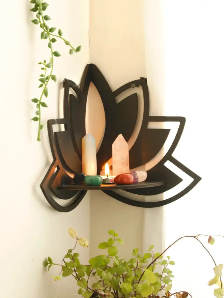 Black metal lotus floating wall shelf with flat open center holding candles and crystals by decorbites