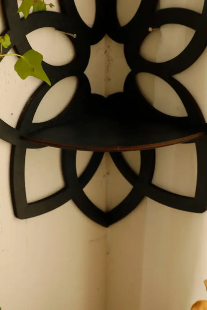 Black floral-patterned metal lotus floating wall shelf with curved surface and decorative cutouts for home decor