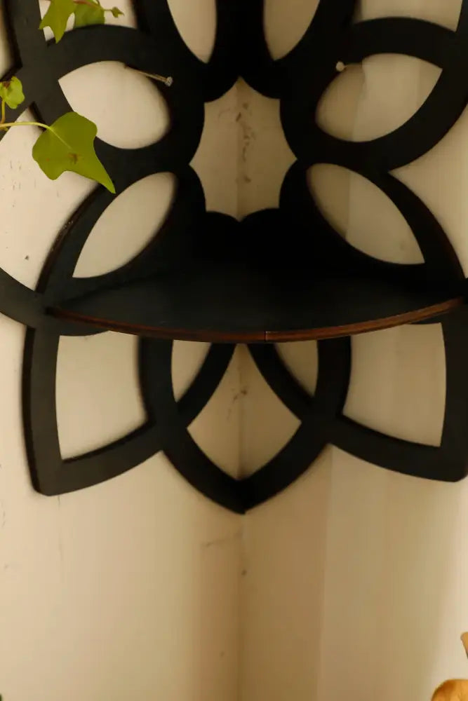 Black floral-patterned metal lotus floating wall shelf with curved surface and decorative cutouts for home decor