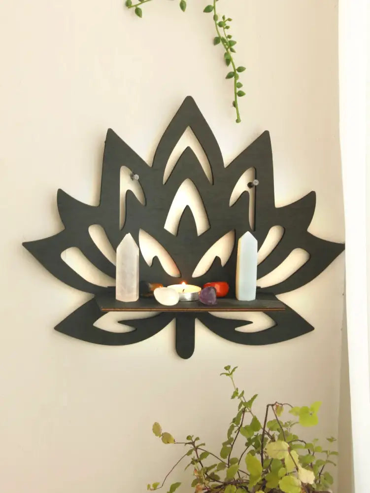 Black wooden lotus floating wall shelf with central slot holding crystals and decorative items by DecorBites™