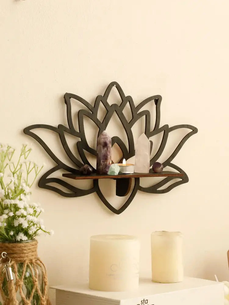Dark brown metal lotus floating wall shelf with central wooden platform holding crystals and candles by decorbites