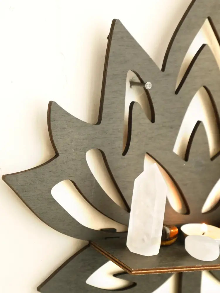 Gray laser-cut wooden lotus floating wall shelf featuring a small shelf with white quartz and candles for decor