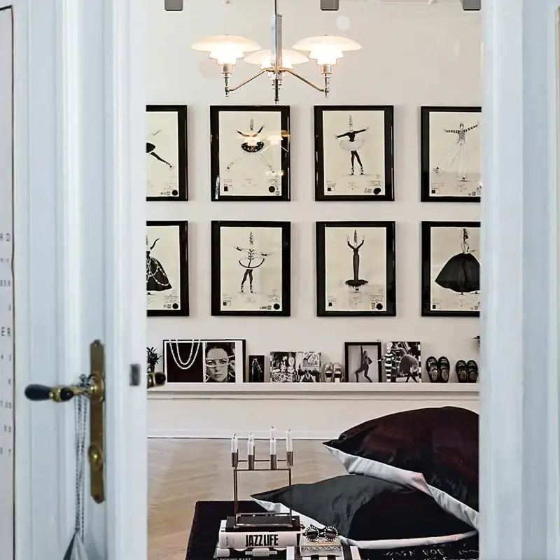 Black-framed black-and-white dance illustrations on white wall with decorbites lotus glass chandelier pendant light
