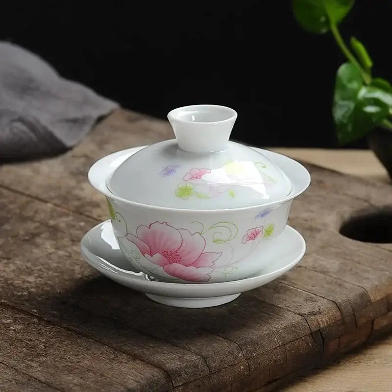 A delicate white porcelain gaiwan tea set with hand-painted pink floral design and green vines by decorbites lotus