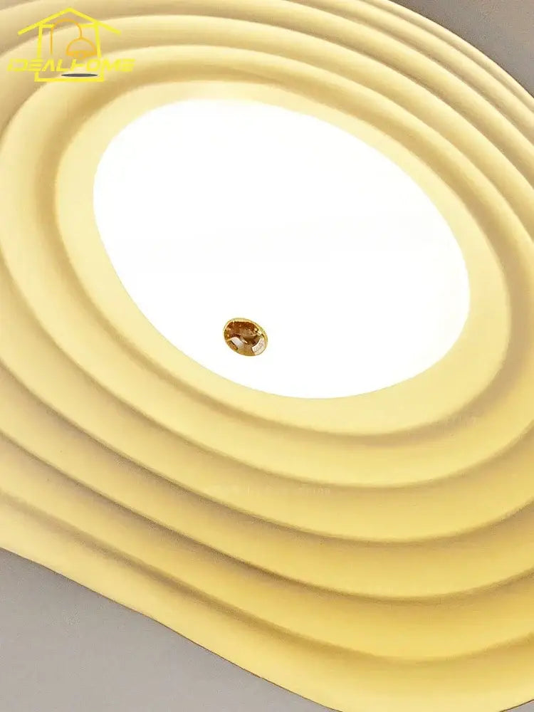 Cream-colored decorbites lotus leaf ceiling light with concentric rings and central amber gemstone accent in resin
