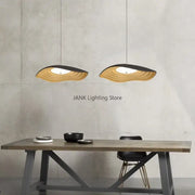 Two modern decorbites lotus leaf chandelier pendant lights with layered wave design in natural wood and black finish hanging above table