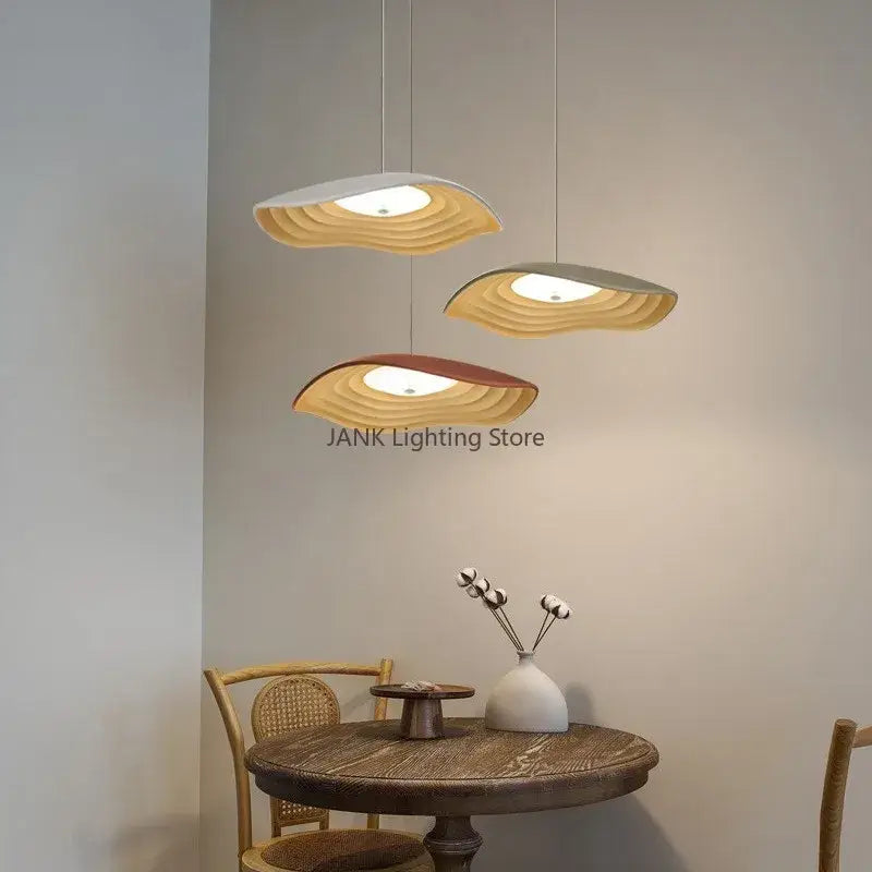 Three modern decorbites lotus leaf chandelier pendant lights with layered wooden shades in white beige and terracotta tones above dining table