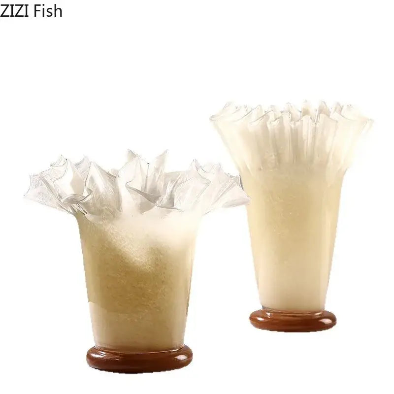 Two translucent cream-colored glass vases with lotus leaf edge fluted tops and brown ceramic bases for room decor
