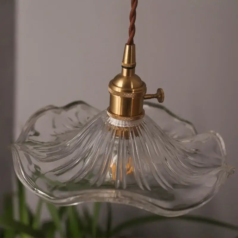 A clear hand-blown lotus leaf glass pendant light with fluted design and brass hardware by DecorBites lotus leaf