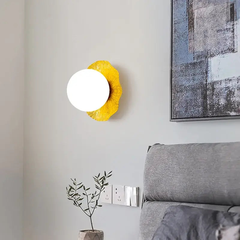 A modern decorbites lotus leaf wall lamp with bright white circular light and vibrant yellow textured petal base