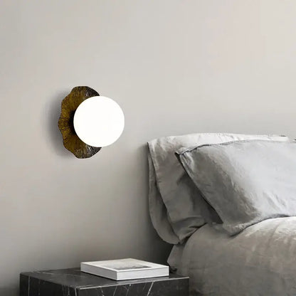 A modern wall lamp with a white glass shade and ornate bronze decorbites lotus leaf led base for Nordic living room