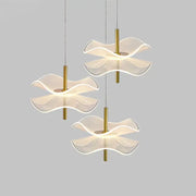 Three modern DecorBites™ lotus leaf pendant lights with translucent wave glass shades and gold metal stems for bedroom use