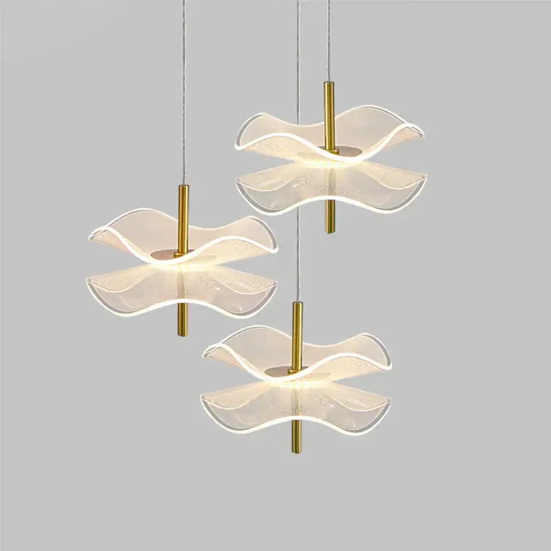 Three modern DecorBites™ lotus leaf pendant lights with translucent wave glass shades and gold metal stems for bedroom use