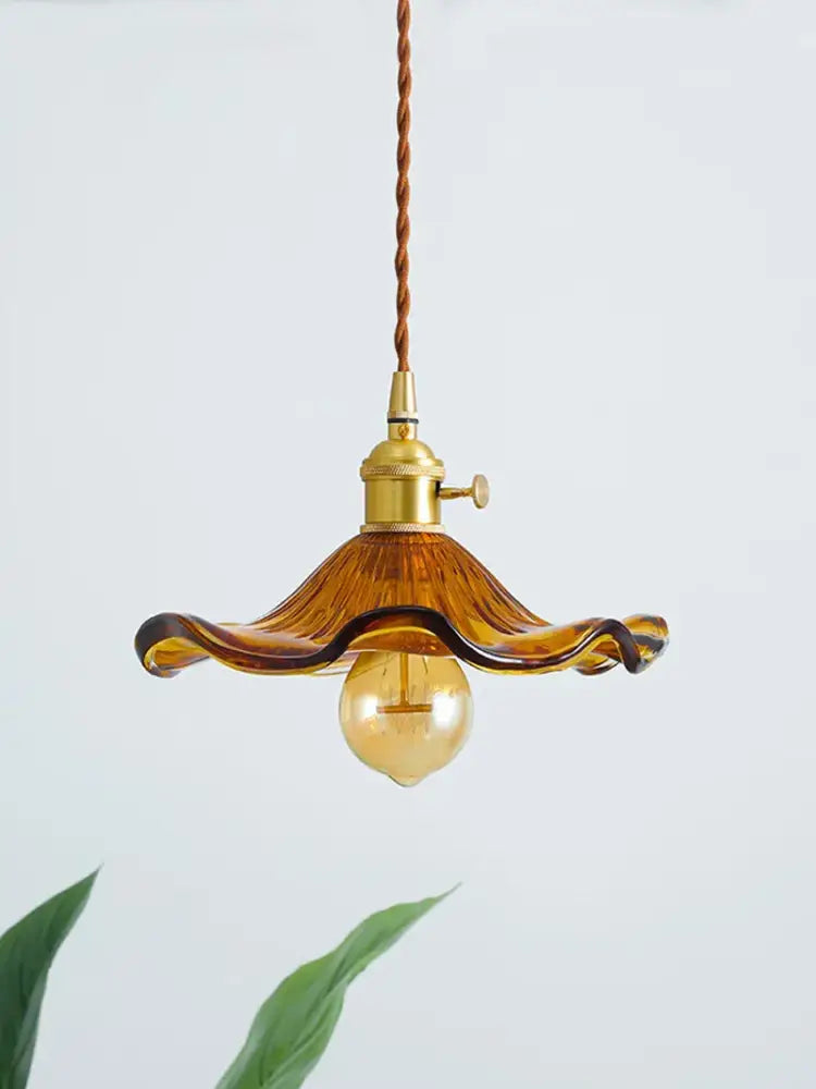 A warm amber glass pendant light with wavy petal design and brass hardware in decorbites lotus leaf pendant lights