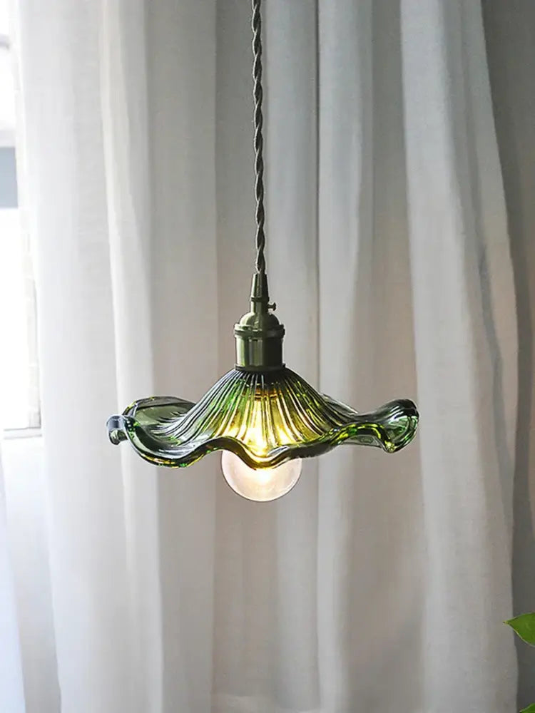 A delicate green glass decorbites lotus leaf pendant light with wavy petal design and exposed bulb for modern interiors
