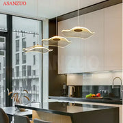 Three gold-toned decorbites lotus leaf single pendant lamps with modern fan-like design hang above kitchen island