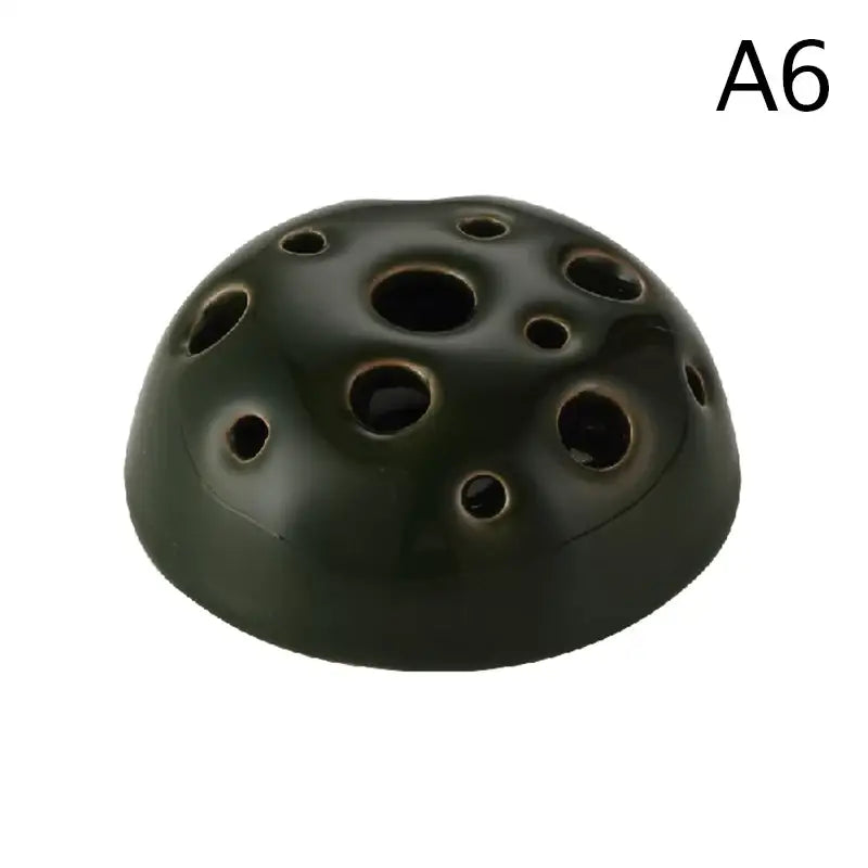 Dark green ceramic vase shaped like a lotus seedpod with multiple circular holes in stone sand texture design