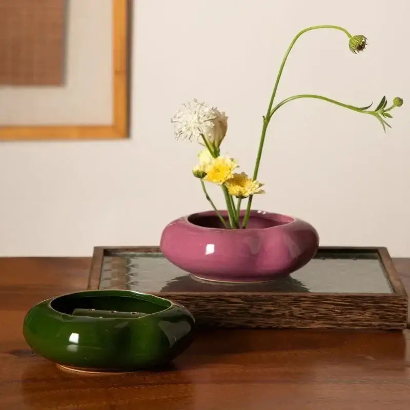 A glossy magenta ceramic vase from DecorBites lotus seedpod set holds delicate white and yellow stone sand flowers