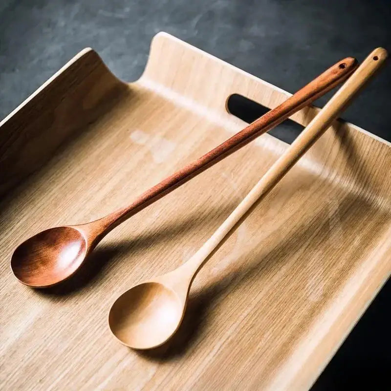 Two polished light-toned decorbites lotus wooden spoons with natural grain rest on a matching wooden tray for cooking