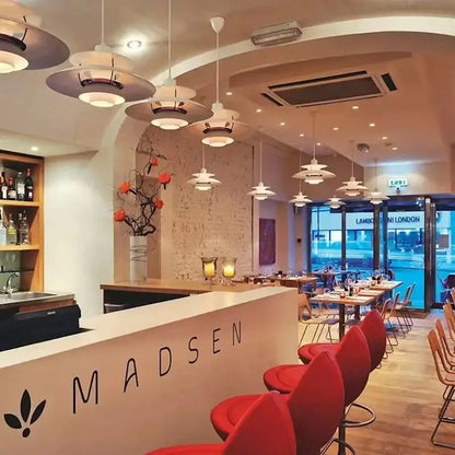 Red upholstered bar stools with curved backs and metal legs beside a loui led pendant light in kitchen setting