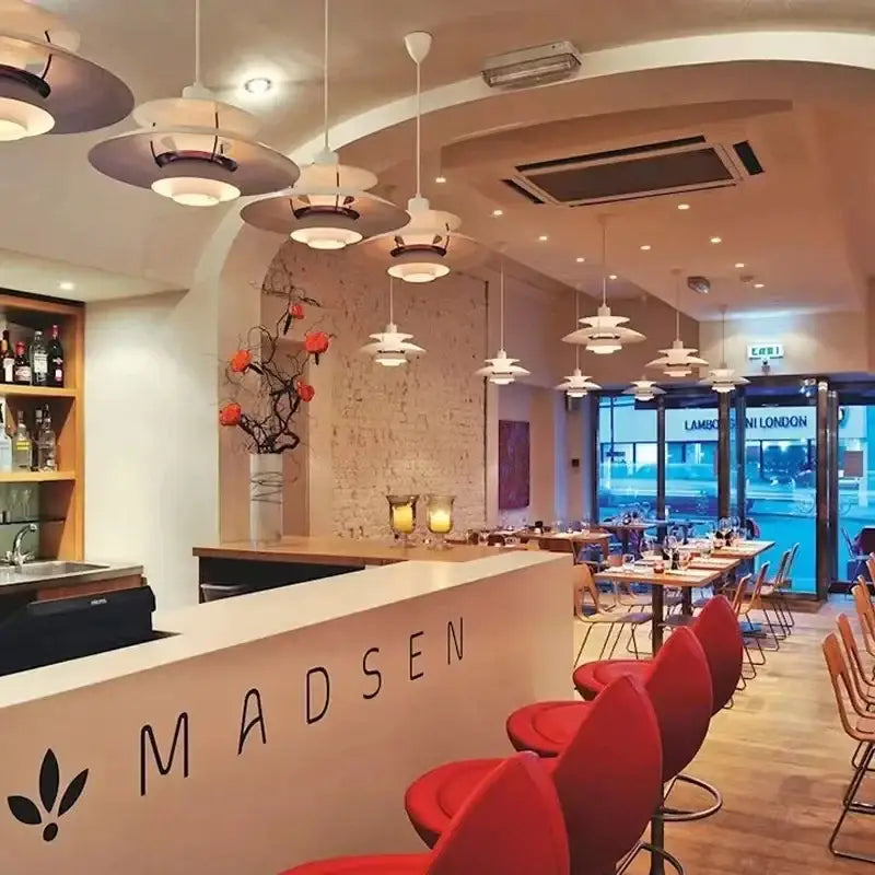 Red upholstered bar stools with curved backs and metal legs beside a loui led pendant light in kitchen setting