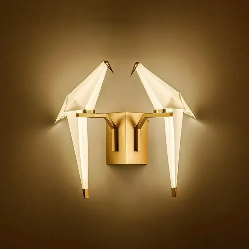 Gold-toned decorbites™ love bird led wall sconce with origami crane figures and translucent wings on a sleek metallic base