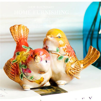 Two ceramic love birds porcelain figurines with glossy glaze in red yellow floral and warm orange tones by DecorBites