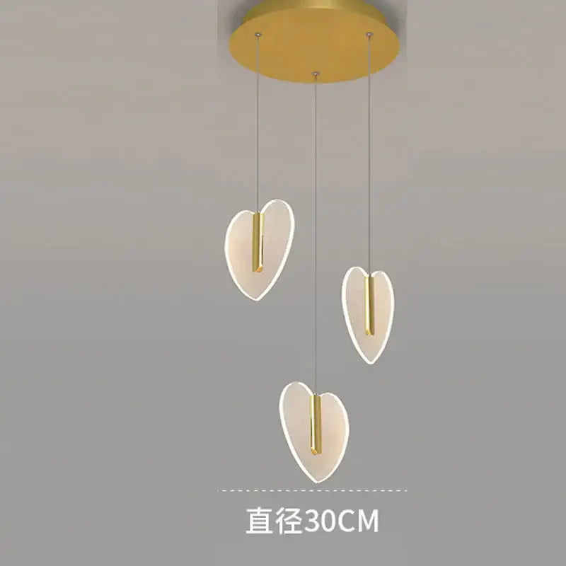 Modern gold-toned pendant light fixture with three glowing heart-shaped shades from decorbites love chandelier