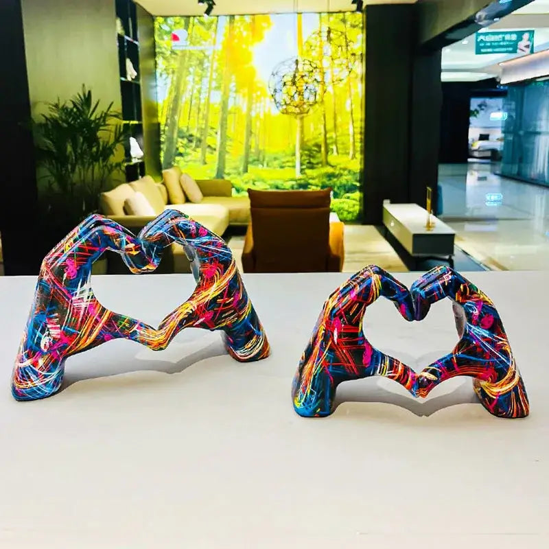 Two vibrant decorbites™ love gesture sculptures with glossy finish and neon paint splatter in blue pink orange and purple