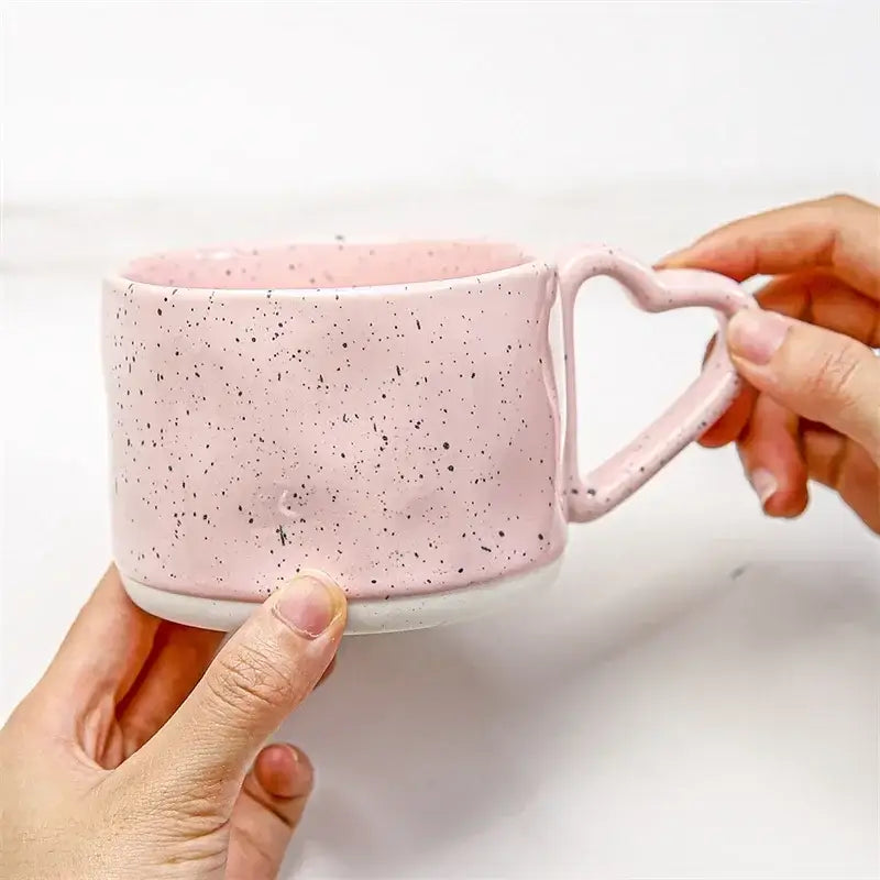 A pink speckled ceramic mug with a heart shaped handle from decorbites love handle ceramic collection for tea and coffee